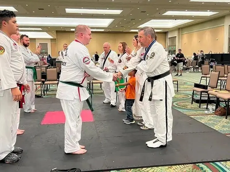 Martial arts students shaking hands during a self defense belt promotion ceremony.