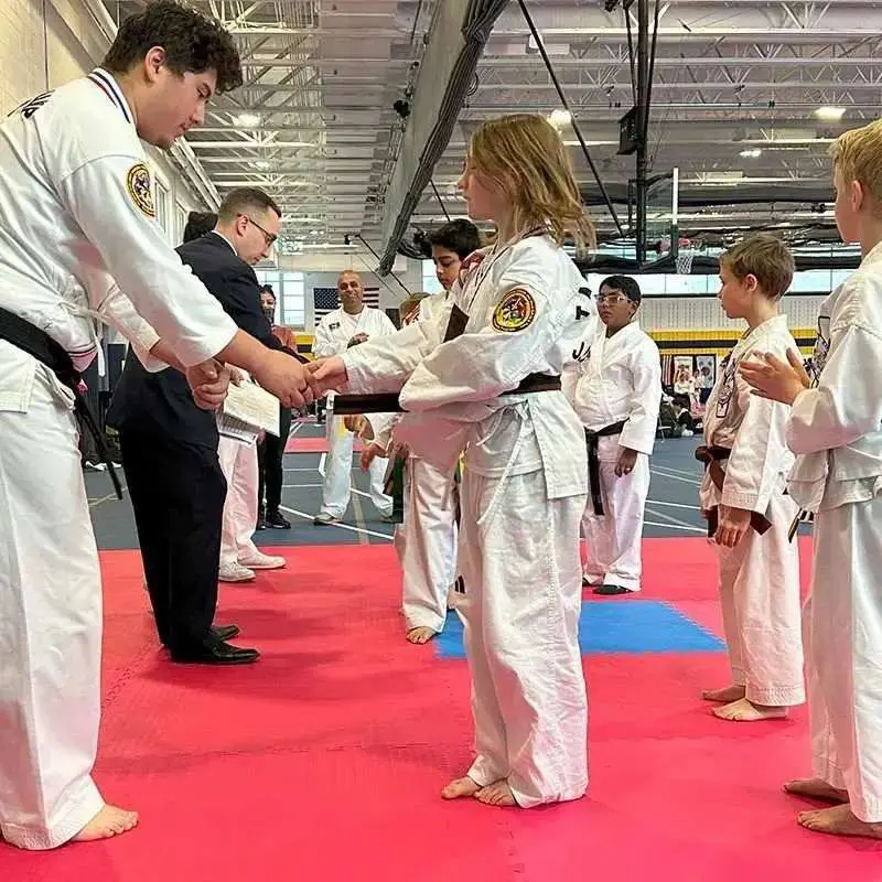 Student receiving a new belt during a self defense graduation ceremony.