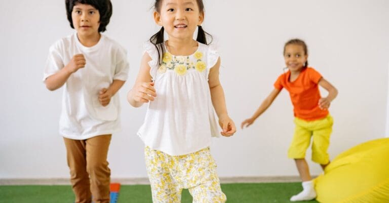 Three young children playfully running during a warm-up game in a preschool Taekwondo class.